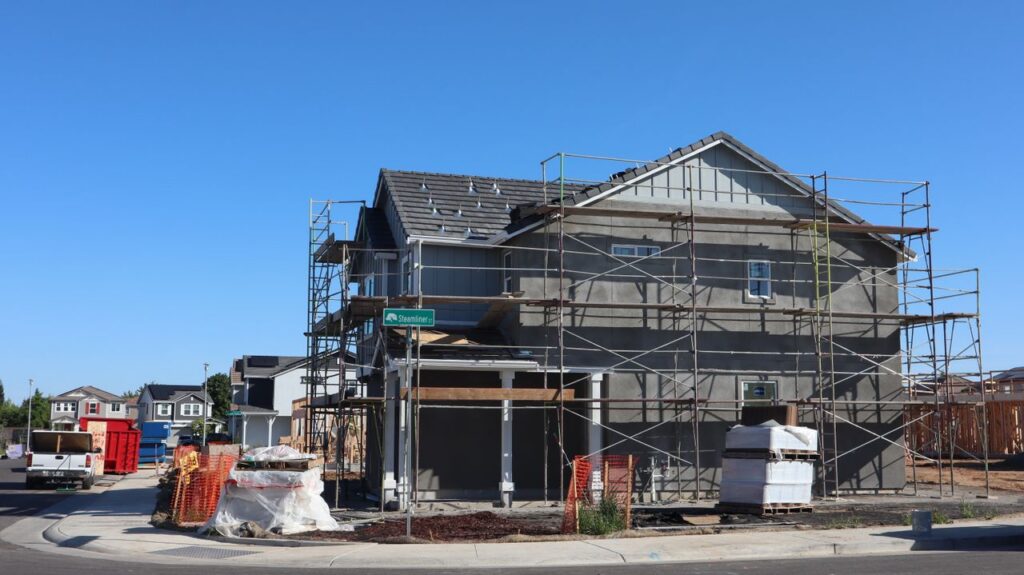 A new housing development under construction in Elk Grove, California with visible scaffolding and materials.